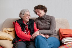 Eine ältere Dame und eine jüngere Frau sitzen gemeinsam auf einem Sofa | © Peter Maszlen - stock.adobe.com